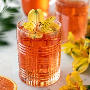 Dark orange drink in glass with flower